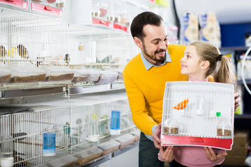Father and daughter enjoying their purchase of canary bird in pet shop