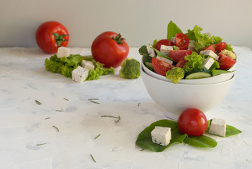 Lettuce leaves, cherry tomatoes, cucumber, broccoli and tofu salad on white background.
