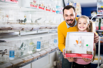 Father and daughter enjoying their purchase of canary bird in pet shop