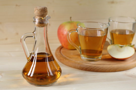 Apple cider and fruit on wooden background.