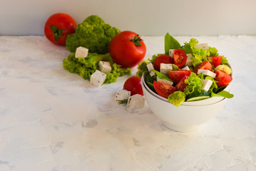 Lettuce leaves, cherry tomatoes, cucumber, broccoli and tofu salad on white background.