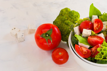 Lettuce leaves, cherry tomatoes, cucumber, broccoli and tofu salad on white background.