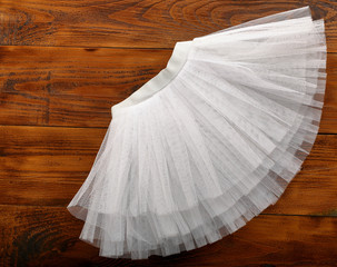 White tutu skirt on wooden background with empty space for text - obrazy, fototapety, plakaty