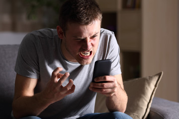 Angry man with a mobile phone at home