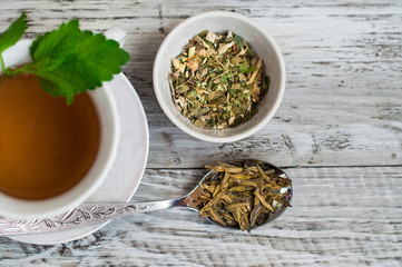 Green tea with mint, drink in a cup close up. On a wooden, light background.