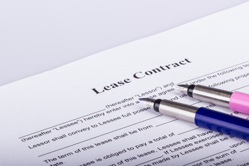 Two fountain pens on the first page of a lease contract, waiting for both parties to sign