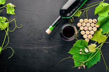 Grape motive. A bottle and a glass of wine and grape leaves. Top view. Free space.