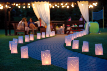 Lantern summerhouse and night lighting path for walks in the garden on blurred background