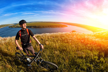 Attractive cyclist standing on the hill with mountain bicyclist against beautiful river.