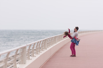 mother and cute little girl on the promenade by the sea