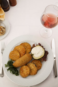 Breaded and fried red bell pepper and eggplant arranged on a plate, Wine bottle and wineglass in background, Traditional dish in elegant setting, Selective focus with soft light