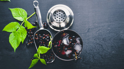 Cocktail of fresh black currant with ice, on a wooden background. Top view. Free space.