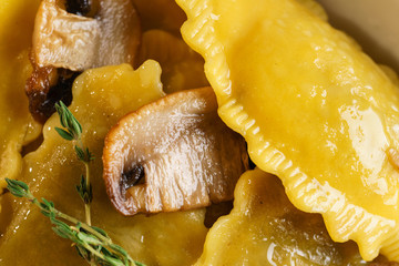 Freshly prepared pasta ravioli and fried champignons mushrooms cut into slices. The meal is decorated with a sprig of rosemary. Traditional Italian homemade food. Macro Closeup.