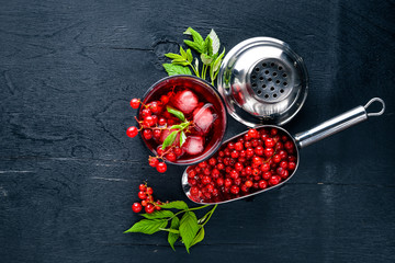 Cocktail of fresh red currant with ice, on a wooden background. Top view. Free space.