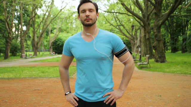 Handsome fitness man doing stretching exercises with head and neck in the park before run. Slow motion. Close up