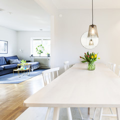 square image of a kitchen table with bunch of tulips and open view into the lviing-room