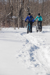 Attractive couple riding fat bikes in the snow