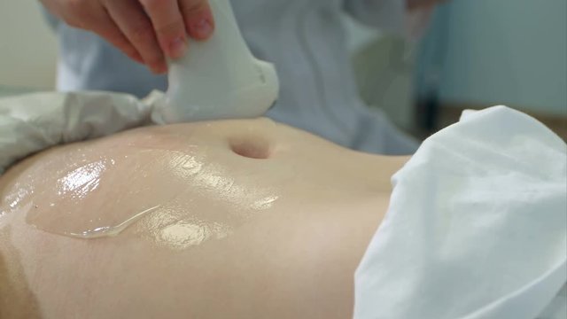 Doctor moving ultrasound probe on pregnant woman's stomach