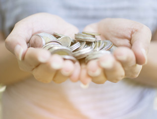 Female holding a pile of coins by two hand