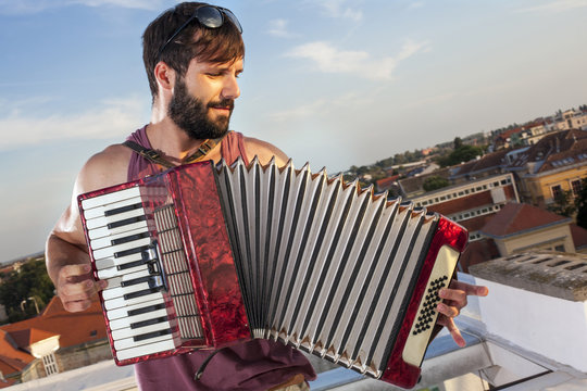 Young man playing accordion on roof terrace