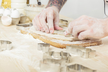 Man chef in uniform makes cookies with baking forms