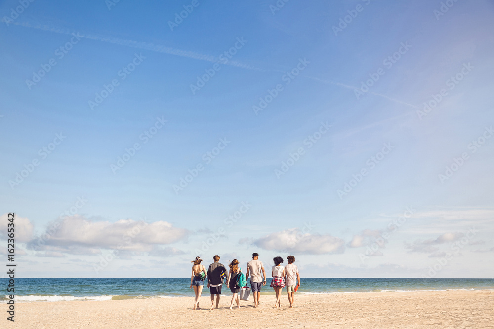 Canvas Prints young people walking on the beach carrying a cooler box