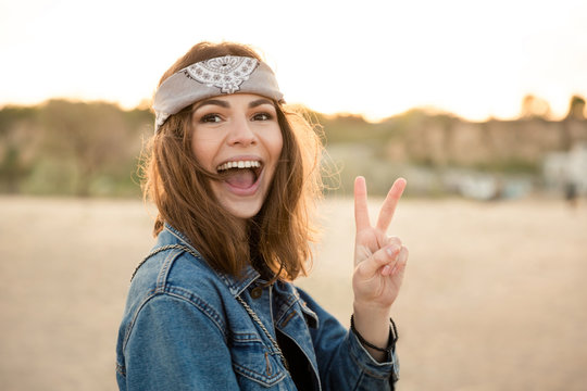 Happy young girl showing peace gesture and looking at camera
