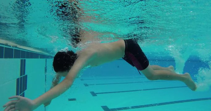 Young asian boy swims freestyle and does tumble turn
