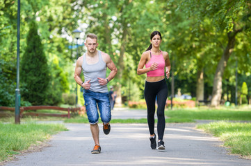 Obraz premium sport woman and man running together in a park in summer