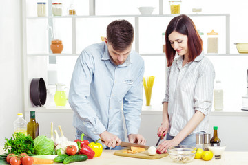 Loving happy couple preparing healthy salad of fresh vegetables in  kitchen