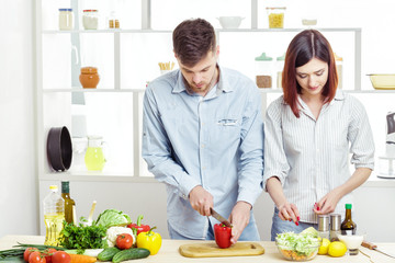 Loving happy couple preparing healthy salad of fresh vegetables in  kitchen