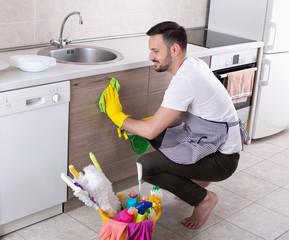 Man wiping kitchen cabinets