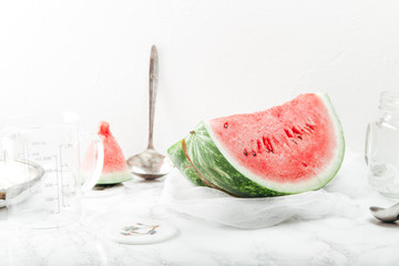 Cooking refreshing watermelon and strawberry lemonade with lime juice, ginger and honey on marble table and white background. Summertime beverage concept. Copy space