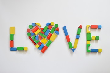 colorful wooden toy blocks shaping the form of a heart as an O in the word LOVE