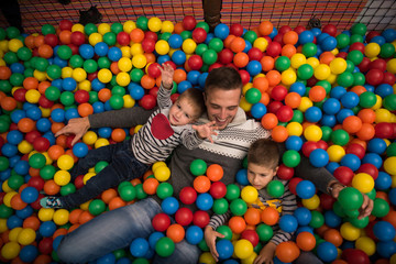 Fototapeta na wymiar Young dad with kids in a children's playroom