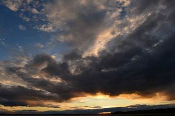 Glowing abyss in the cloudy sky at sunset over the lake