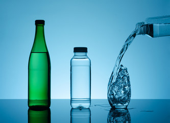 Bottle with creative splashing water in the glass