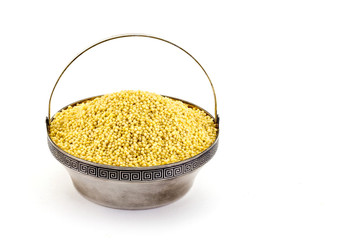 Dry millet in silver bowl isolated on white. Spilled millet.