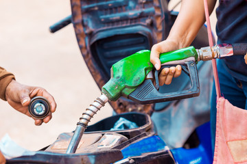 Close-up of a man's hand  filling gasoline fuel to tank of motorcycle in gas station