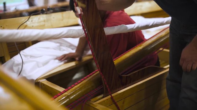 Mature master in glasses with assistant working with newly homemade boat or sailboat in workshop 4k. Teal and orange style. Dust background white sail.