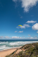 Paraglider with yellow wing above the ocean