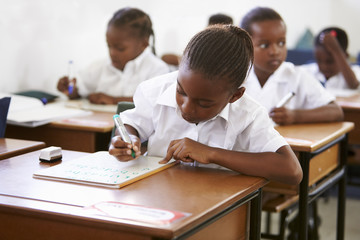Schoolgirl writing at her desk in elementary school lesson