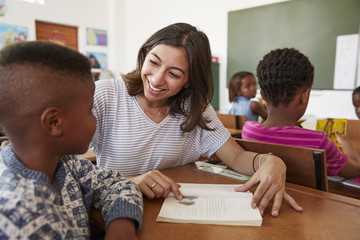 Fototapeta premium Female teacher helping elementary school boy in class