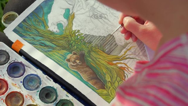 female artist paiting a jungle themed picture  with watercolours, outdoors in a nature

