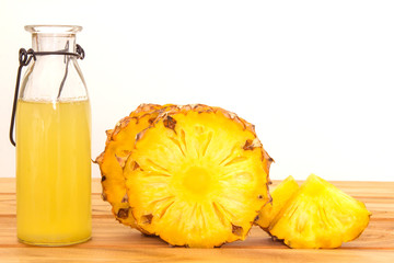The Bottles of pineapple juice with sliced pineapple fruit on wooden table  , summer fruit drink concept