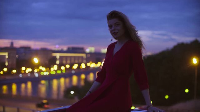 Young woman in red dress is sitting on a parapet