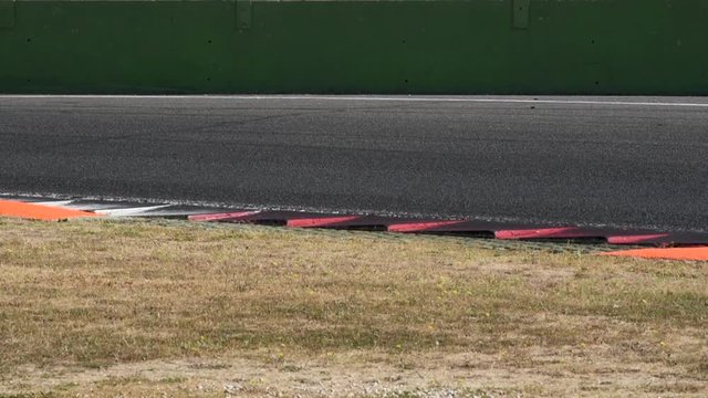 Motorsport racing circuit track with curbs and blurred car crossing frame