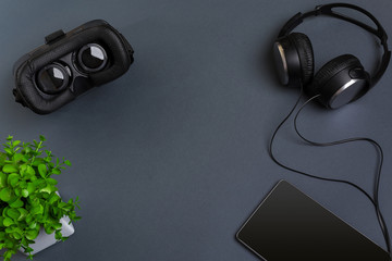 Virtual reality glasses and tablet with headphones on a gray background. Top view