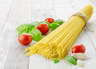 Italian spaghetti pasta and fresh ingredients on a rustic wooden background