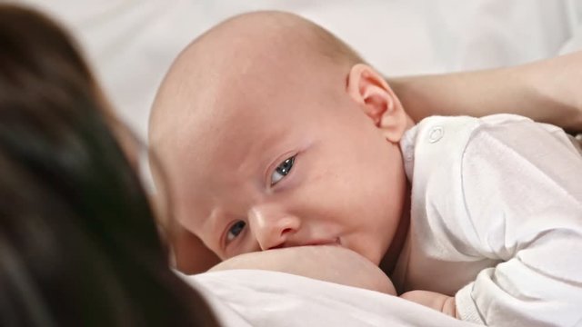 High angle view of cute baby eating milk from breast of mom